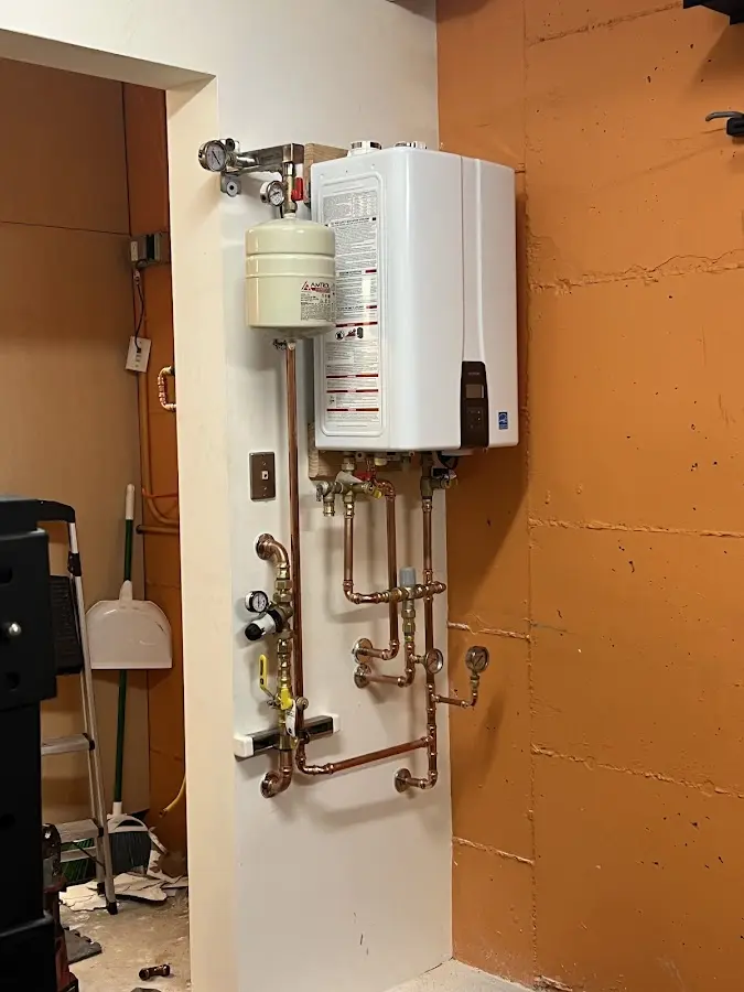 Plumbing technician inspecting water heater connections in Ticonderoga